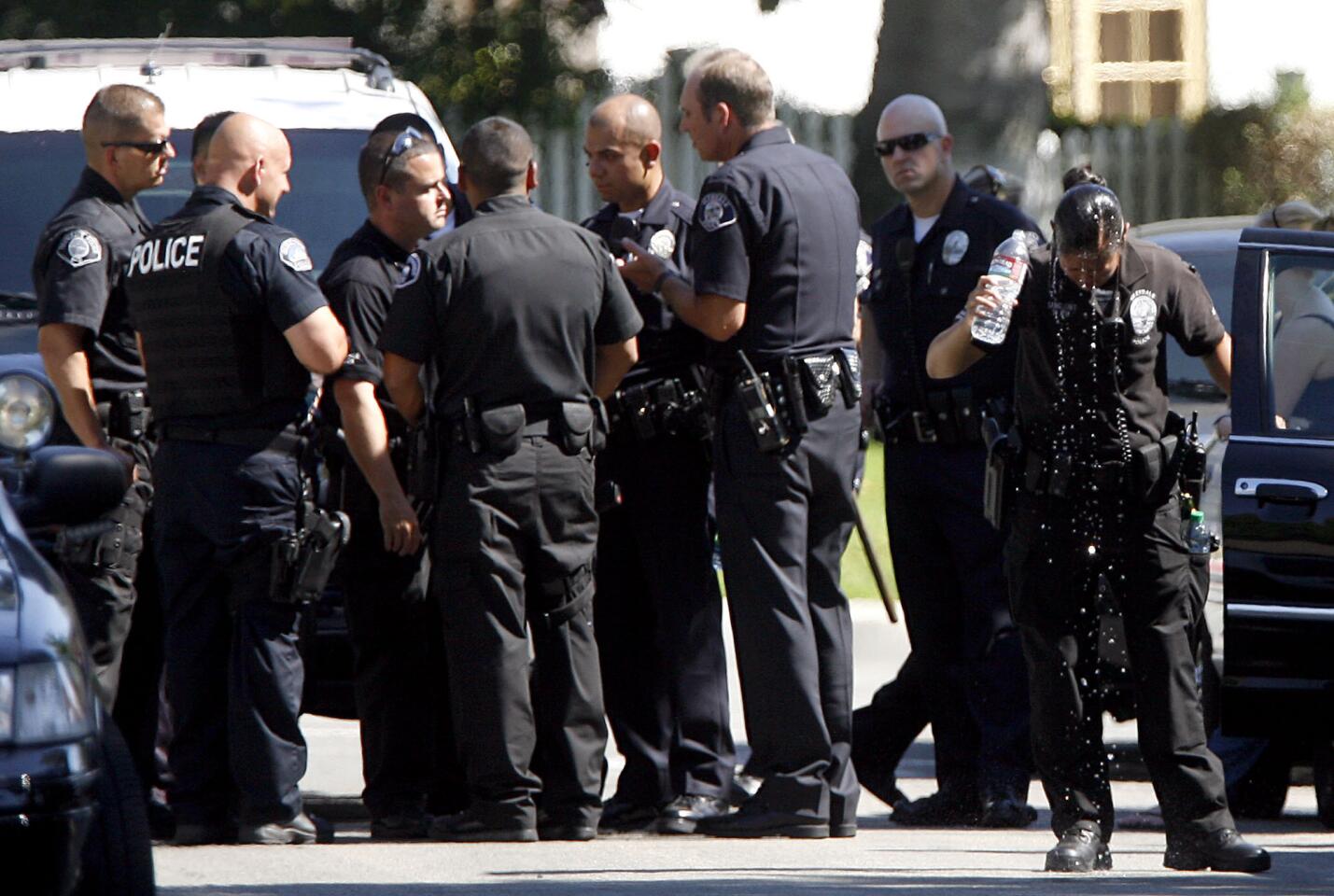 A Glendale Police officer cools down by pouring a bottle of water on her head as other members of the dept. strategize while they look for a burglary suspect on the 1800 block of Cleveland Rd. at Crestview Ave. in Glendale on Thursday, Sept. 13, 2012.