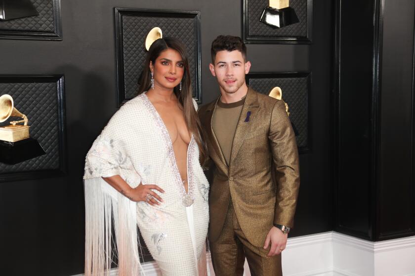 A man and a woman in formalwear arrive at an awards show