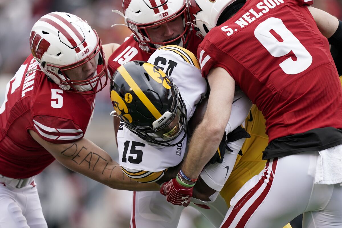 Wisconsin's linebackers Leo Chenal (5) and Nick Herbig (19), and safety Scott Nelson (9), wrap up Iowa running back Tyler Goodson (15) during the first half of an NCAA college football game Saturday, Oct. 30, 2021, in Madison, Wis. (AP Photo/Andy Manis)