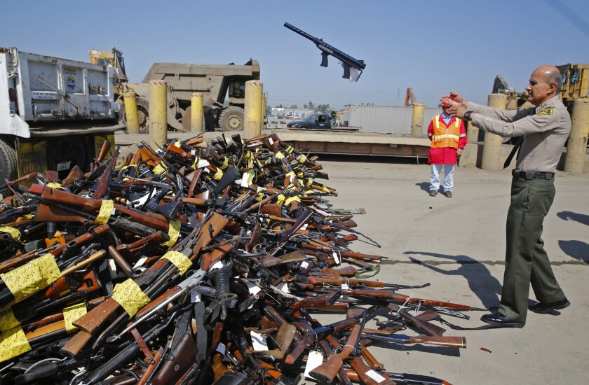 Los Angeles County Sheriff Lee Baca tosses a rifle onto a pile of 5,495 firearms at the Gerdau Steel Mill in Rancho Cucamonga. The guns, collected in Southern California buyback events, were melted down and made into steel reinforcing bar (rebar) for construction uses.