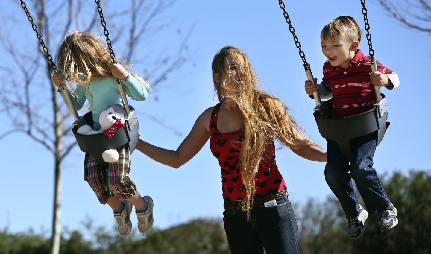 Holly Di Renzo gives her daughter Bella, 4, left, and son Dante, 3, a push, as they ride on the swings at Lost Canyon Park in Simi Valley.