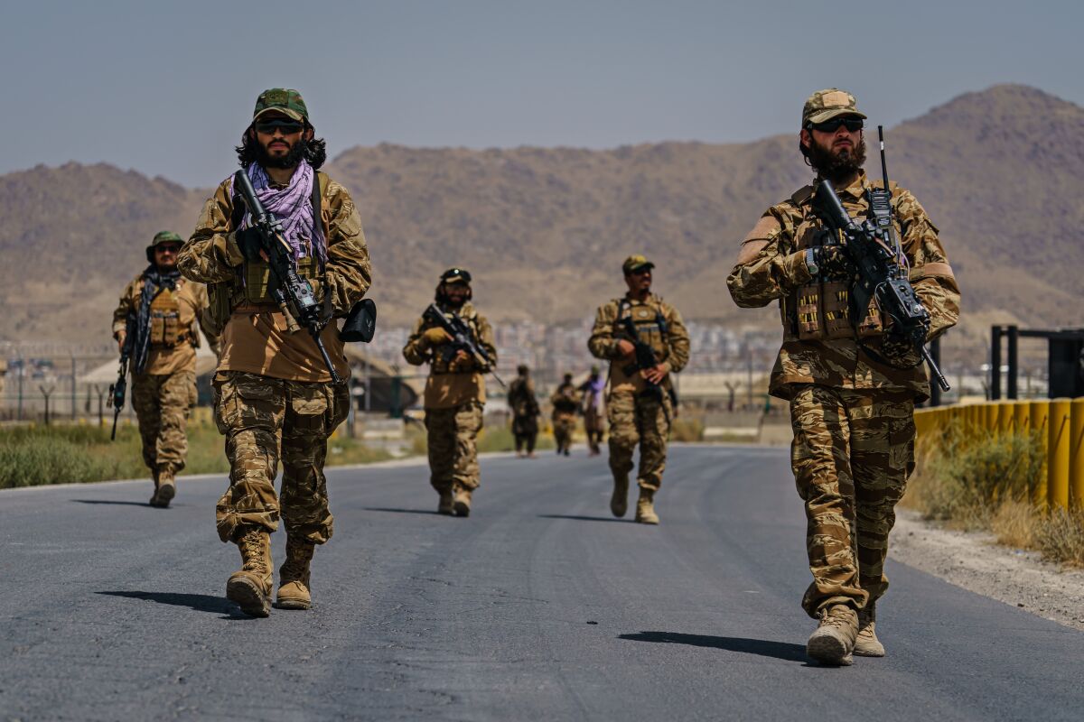 Several Taliban fighters in uniform carry weapons.