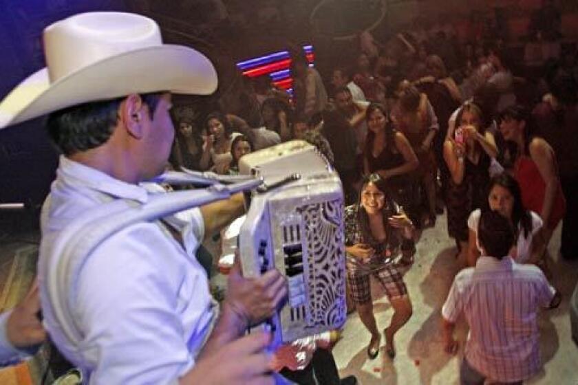 Alfredo Madrigal, a member of Herederos de la Frontera, plays accordion for admiring fans at the Baby Rock club in Tijuana. His group specializes in traditional Norteño-style ballads.