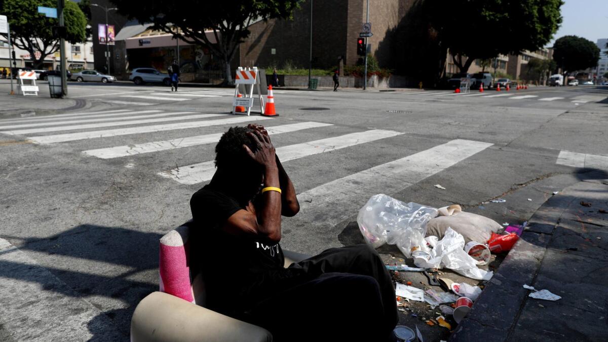 A homeless man sits at the corner of East 6th and Wall streets in downtown Los Angeles on May 30.