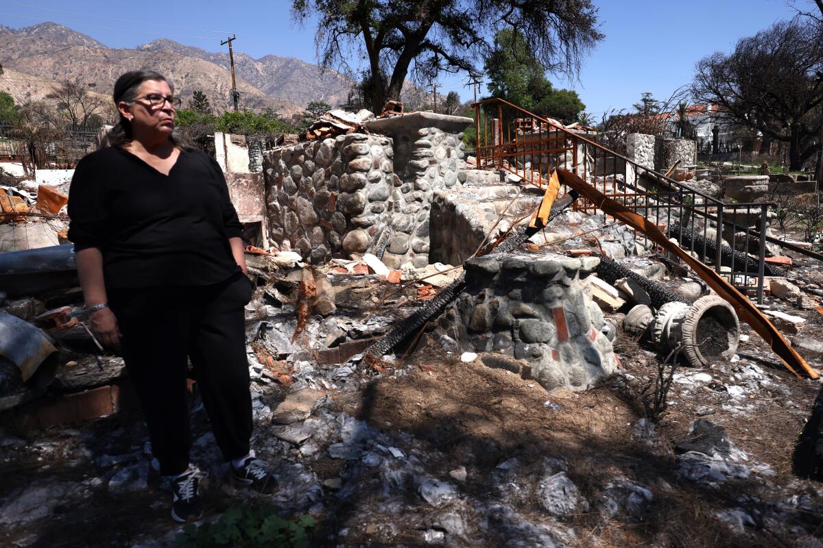 A woman stands in the rubble of her burned down house