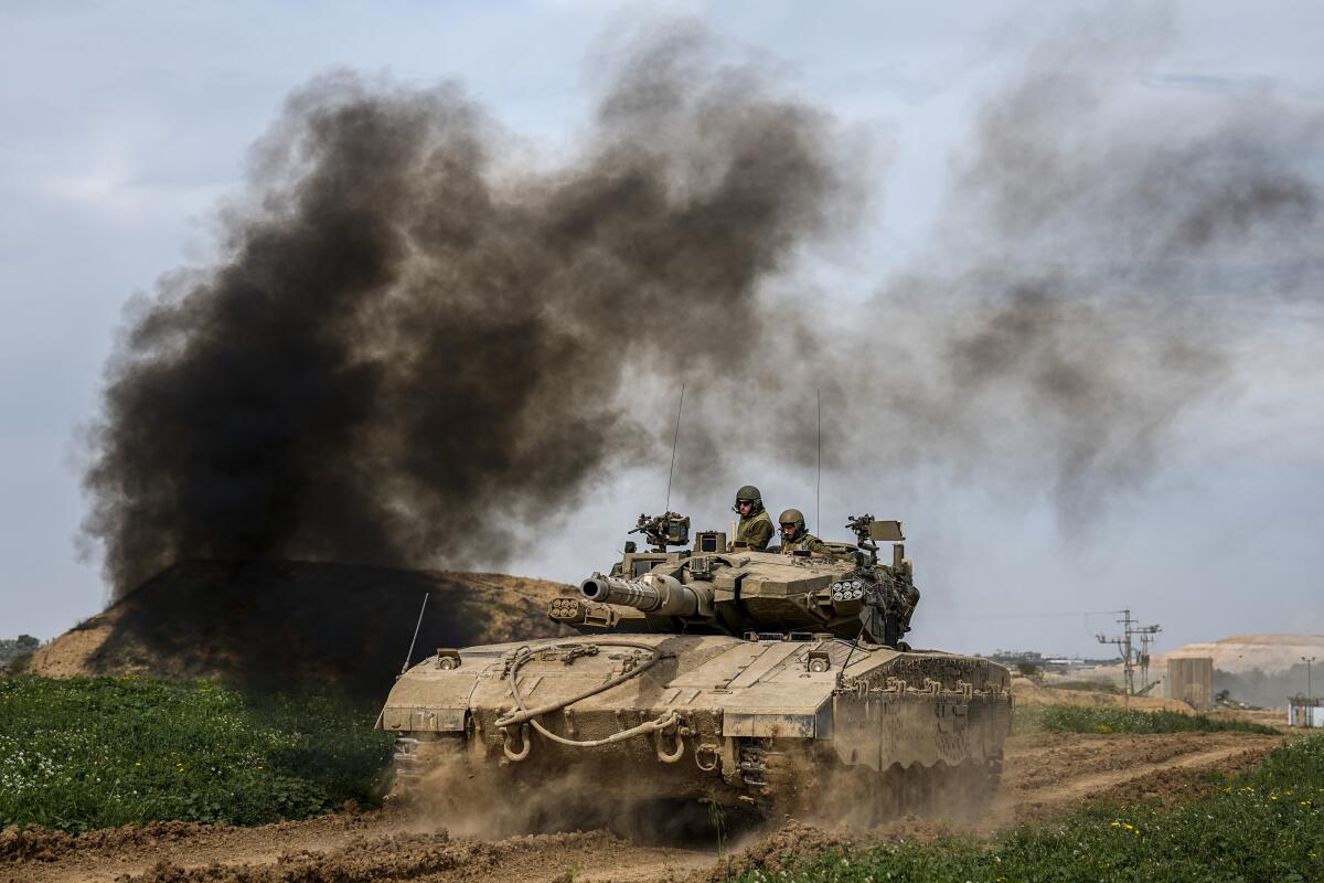 Smoke rises as Israeli soldiers drive a tank on the border with the Gaza Strip, in southern Israel.