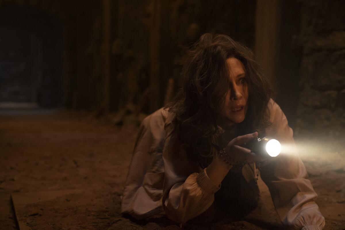 A crawling woman shines a flashlight into the dark.