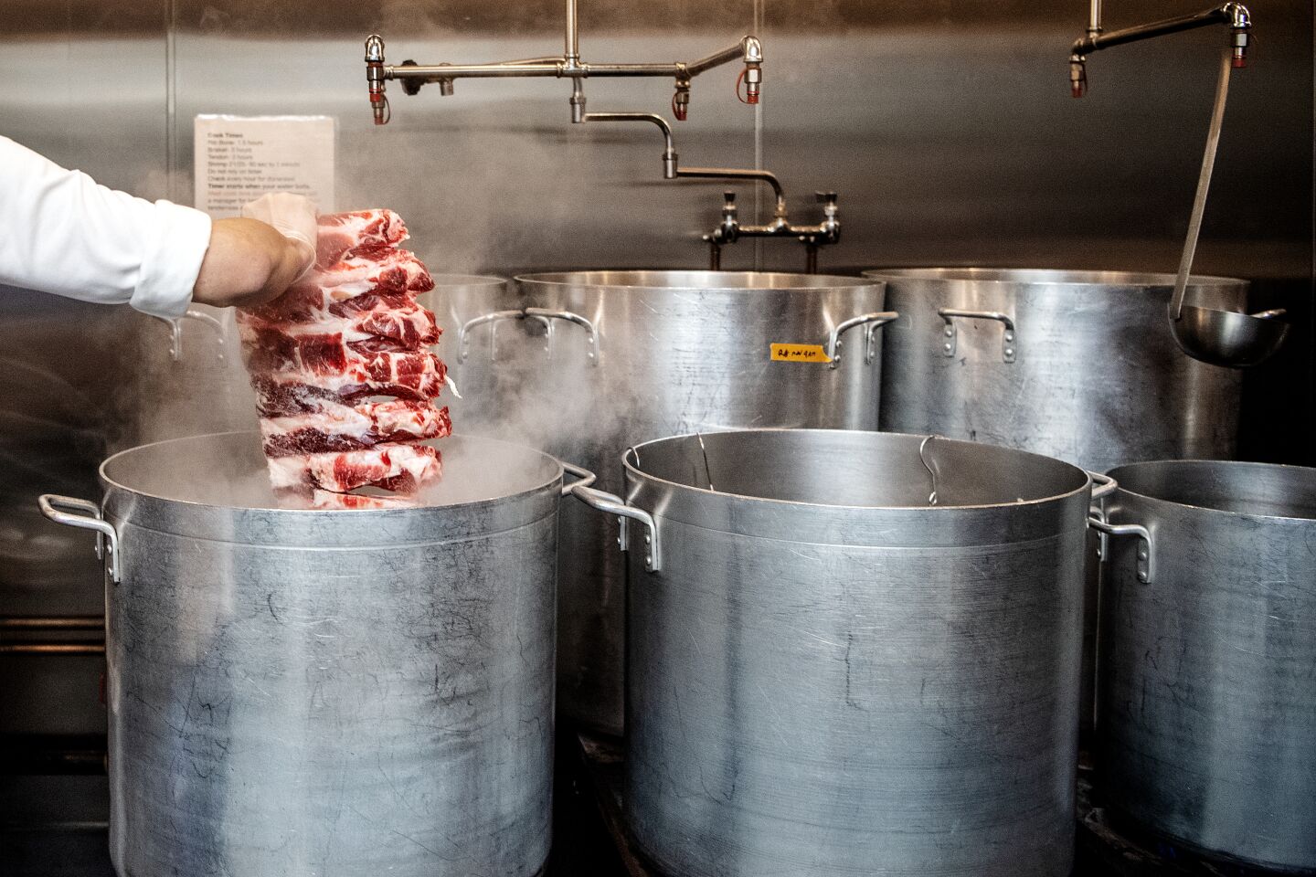 Chef Viet Nguyen drops cuts of meat to pots into begin cooking his pho broth. The entire process takes 48 hours.