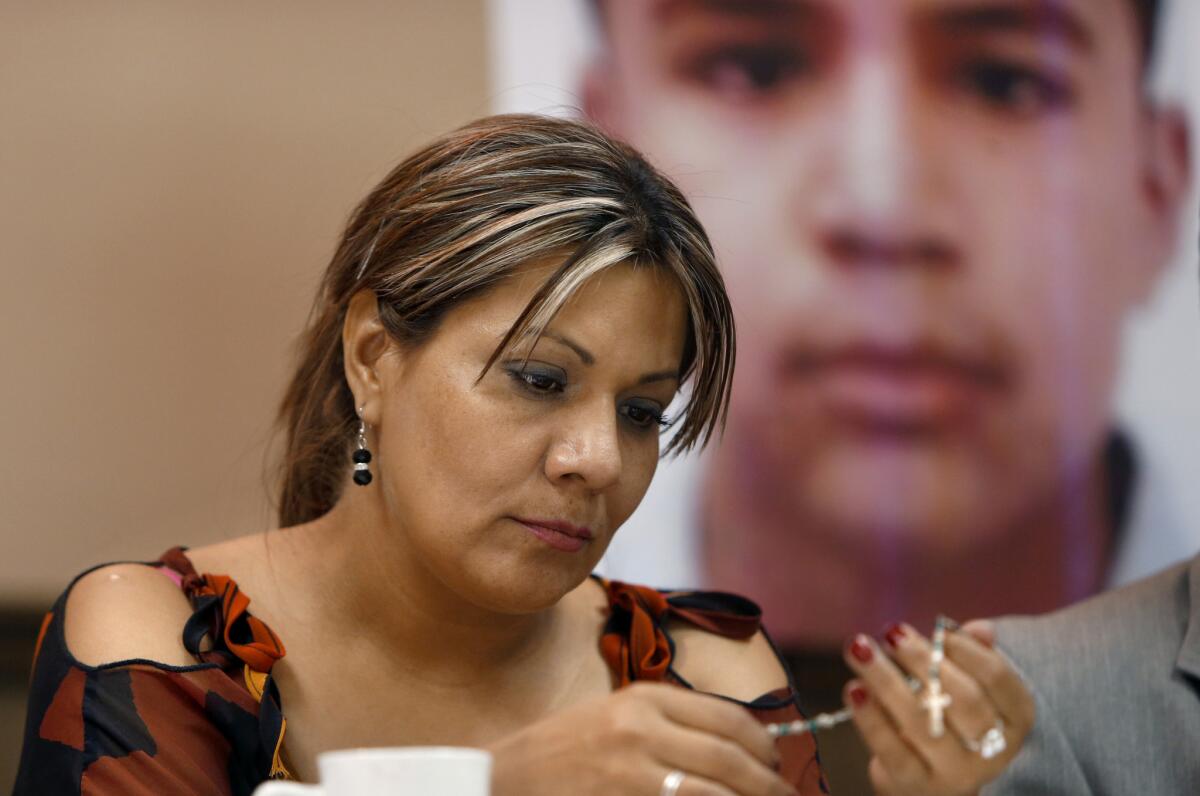 Araceli Rodriguez holds a rosary that belonged to her son Jose Antonio Elena Rodriguez, pictured behind her. He was shot and killed by U.S. Border Patrol agent in 2012.