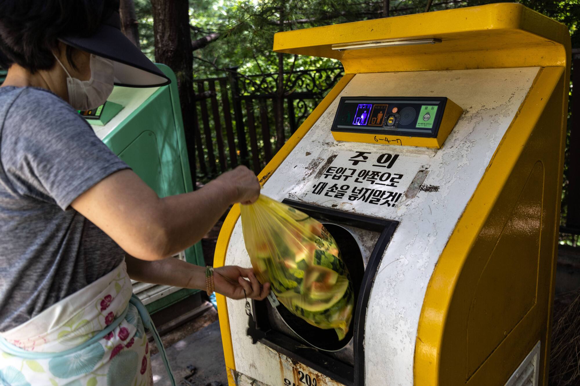 A woman deposits the food waste into a food collecting machine called "CleanNet"