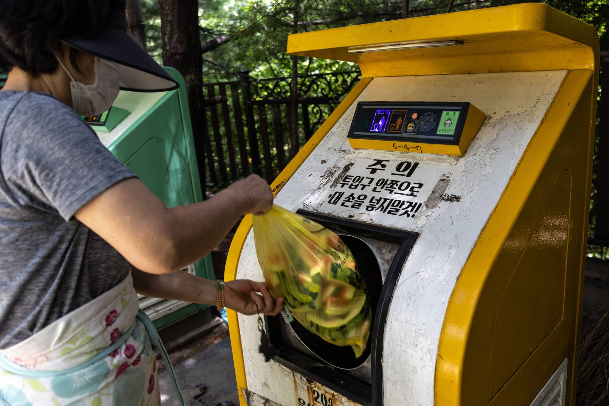 A woman deposits the food waste into a food collecting machine called 