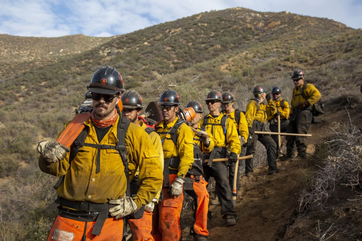 In this undated image provided by the Forestry and Fire Recruitment Program, firefighters from the Forestry and Fire Recruitment Program in pause the Angeles National Forest near Los Angeles. The Forestry and Fire Recruitment Program, a nonprofit, has a $3.4 million budget and has trained more than 3,000 people and helped more than 140 get jobs. (Ed Kashi/Talking Eyes Media for Forestry and Fire Recruitment Program via AP)