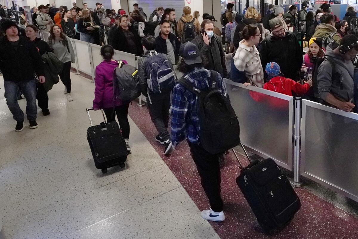 Travelers wheel bags past the line for TSA screening.