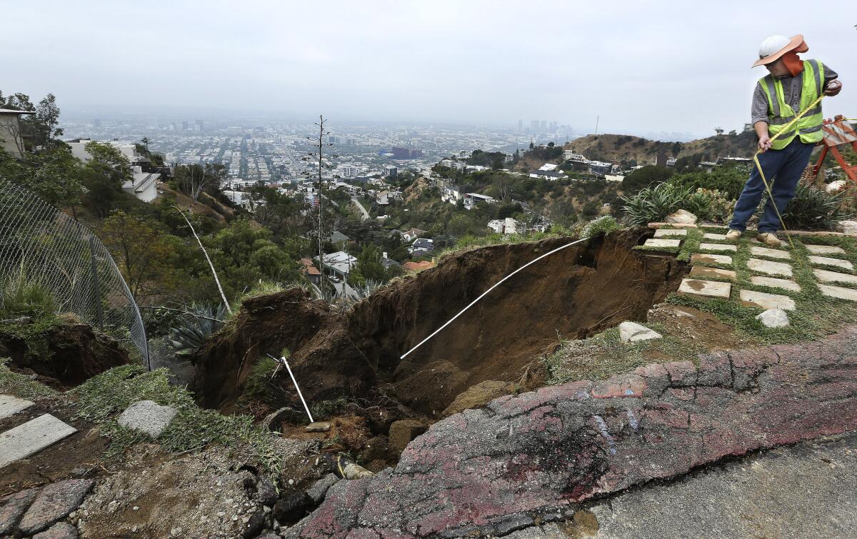A geologist for the DWP takes measurements at the scene of a hillside that gave way on Grandview Dr. in the Hollywood Hills.