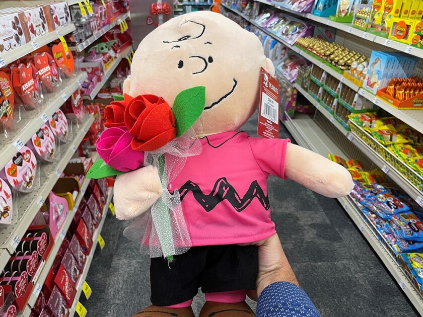 A stuffed Charlie Brown holding a bouquet of flowers 