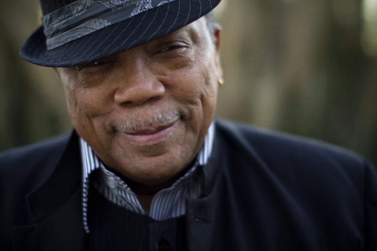 Quincy Jones, wearing a fedora, smiles.