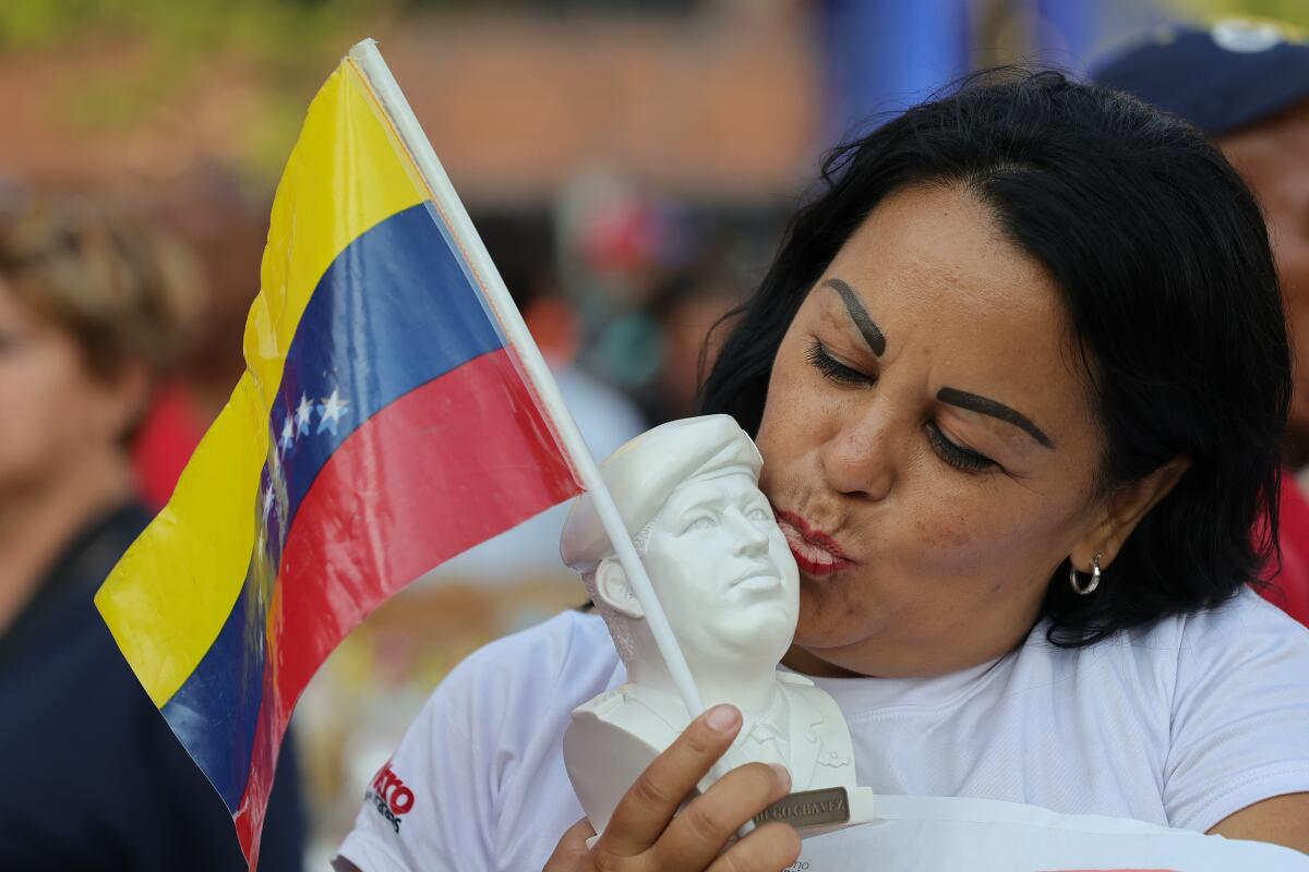 A woman kisses the face of a small Hugo Chavez bust.