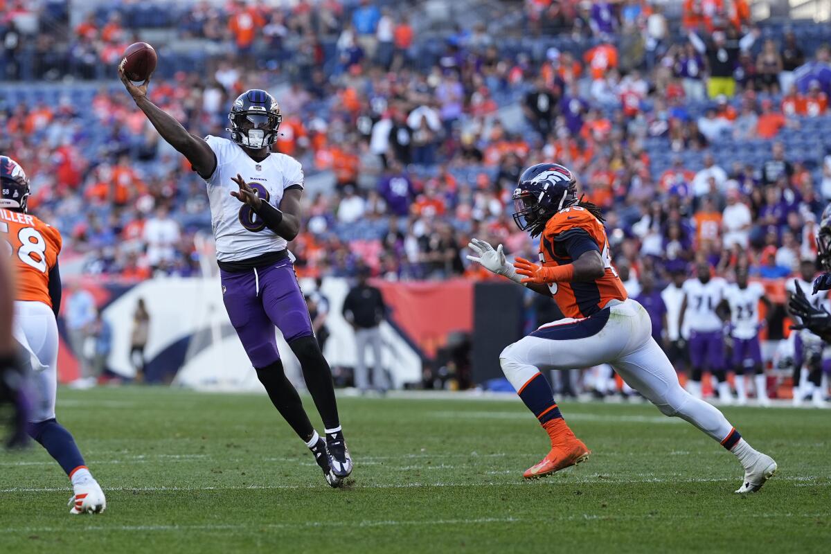 Baltimore Ravens quarterback Lamar Jackson throws as Denver Broncos linebacker A.J. Johnson chases him.