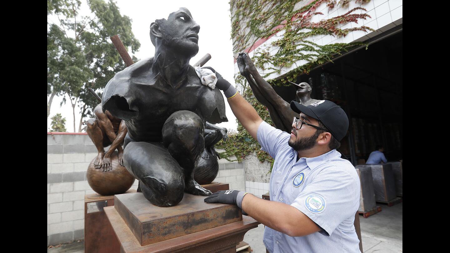 Matthew Manrique polishes the bronze sculpture "El Tiempo," one of nine statues created by renowned Mexican figurative artist Jorge Marín that will be part of a public art installation, "Wings of the City," in historical downtown Santa Ana. The sculptures pay homage to classic Baroque and Renaissance pieces with surreal twists.