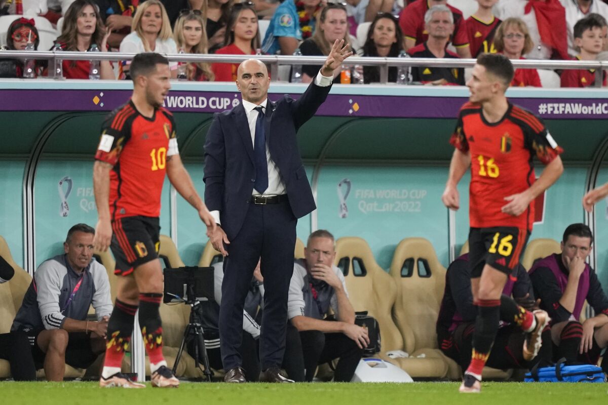 Belgium's Eden Hazard, left, and his brother, Thorgan Hazard, right, are visible as head coach Roberto Martinez talks to his team during the World Cup group F soccer match between Belgium and Morocco, at the Al Thumama Stadium in Doha, Qatar, Sunday, Nov. 27, 2022. (AP Photo/Frank Augstein)