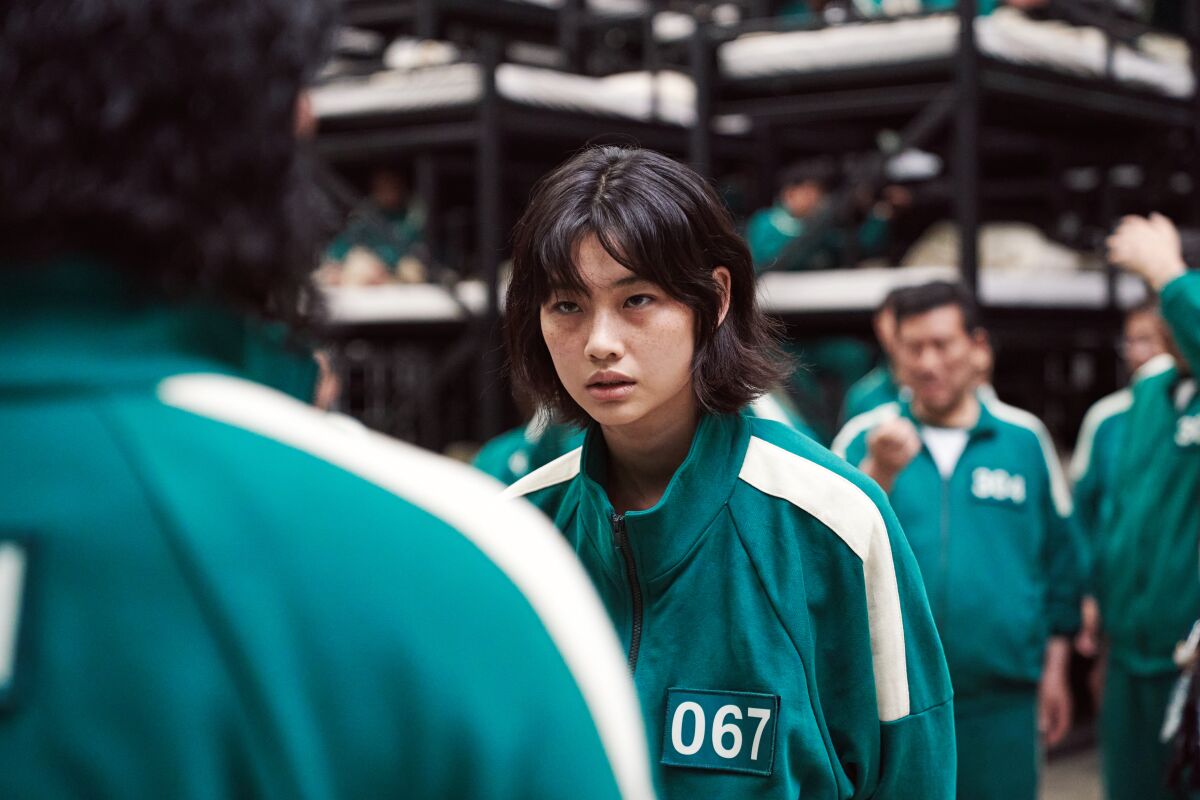 A woman in a green tracksuit with the number 067 printed on it.
