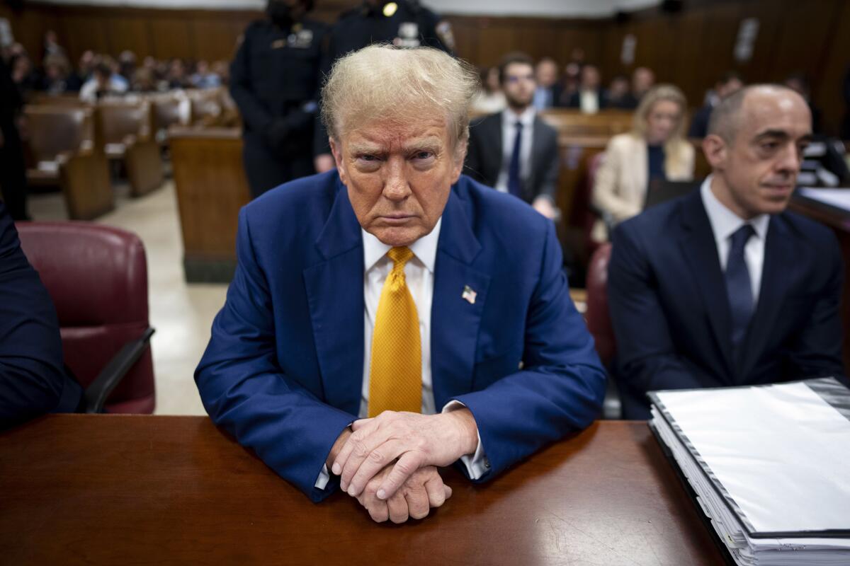 Former President Trump looks straight ahead while sitting at a table in court.