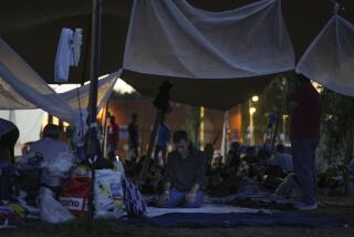 A man prays under a tarpaulin as hundreds of migrants who seek shelter prepared to spend the night outside an overcrowded asylum seekers center in Ter Apel, northern Netherlands, Thursday, Aug. 25, 2022. (AP Photo/Peter Dejong)