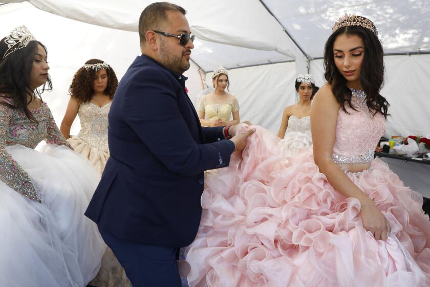 468487-sd-me-hispanic-heritage_NL San Diego, CA October 12, 2019 Alberto Chausse helps Natalie Nevarez, 15, with her dress as models leave the dressing area for Lili's Creations Quincenera Fashion show as The Joe and Vi Jacobs Center hostied it's first Hispanic Heritage Festival. Events included a festival blessing, fashion show, lowrider contest, and aztec and traditional folkloric dancers. © 2019 Nancee E. Lewis / Nancee Lewis Photography.