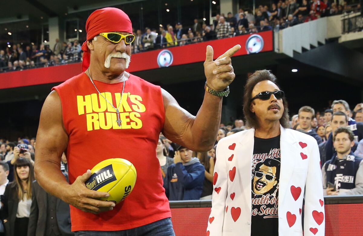 Hulk Hogan gestures to the crowd while attending an AFL game in Australia with Jimmy Hart in 2015.