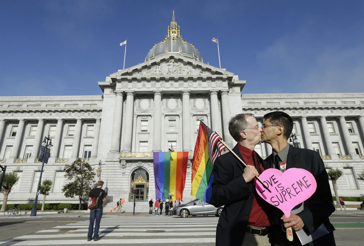 Gay rights advocates John Lewis, left, and his spouse Stuart Gaffney, with the group Marriage Equality USA, kiss across the street from City Hall in San Francisco on Friday following a ruling by the U.S. Supreme Court that same-sex couples have the right to marry nationwide.