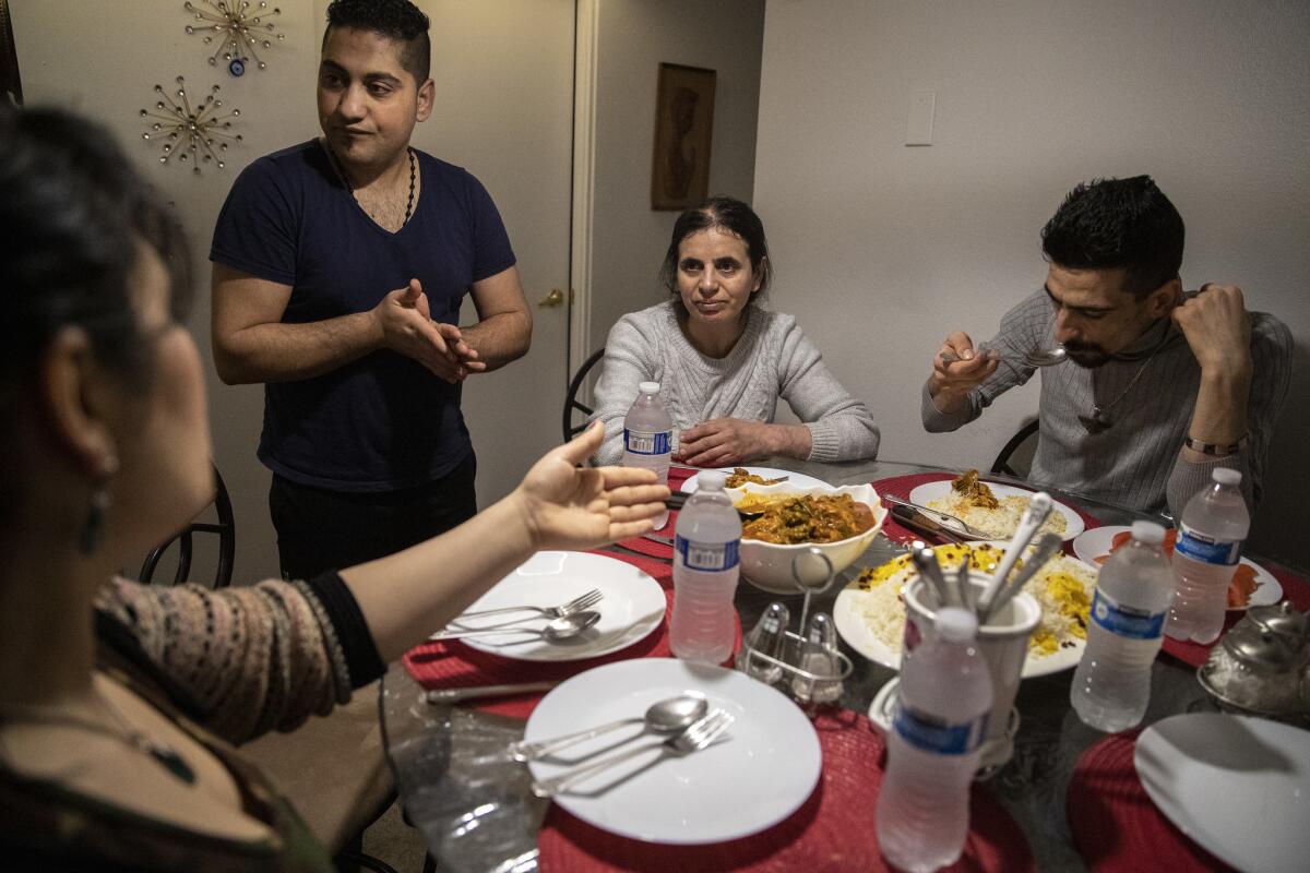 Iranian refugees Sirvan Moradi, right, and his aunt, Saltanat Moradi, center, share their first meal in the United States with hosts Nadia Mousavi and Masoud Veysi in Kent, Wash.
