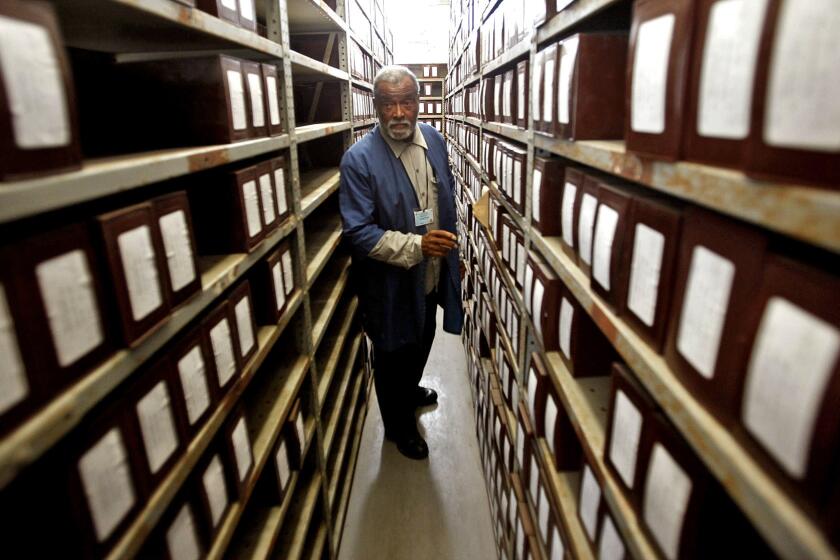 Cemetery caretaker Albert Gaskin stands in a room where hundreds of boxes are stored, each containing the ashes of a person who has been cremated by L.A. County.