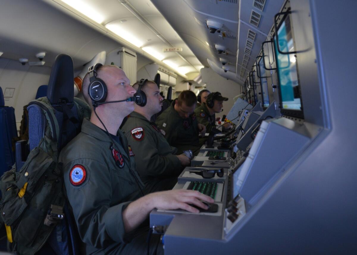 Crew members aboard a P-8 Poseidon assist in the search operation for Malaysia Airlines Flight 370.