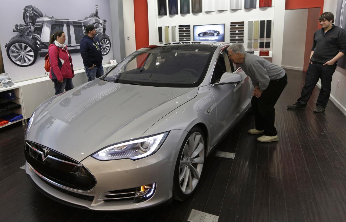 Customers look at a Tesla Model S in a company showroom in Cincinnati.