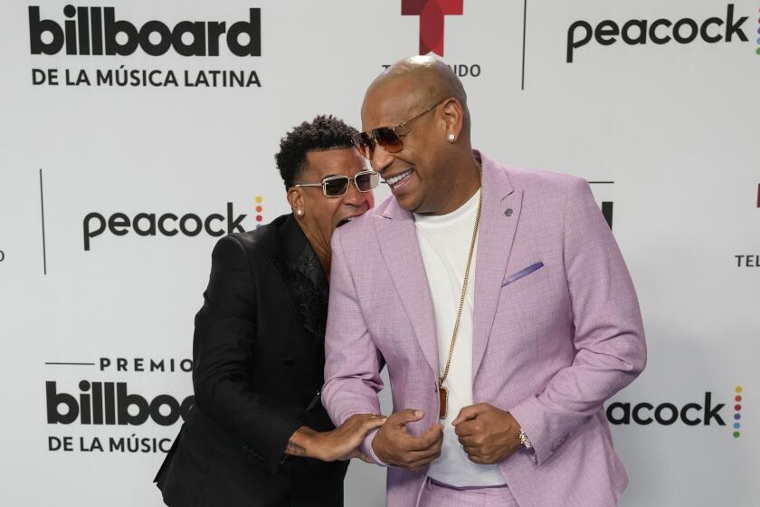 ARCHIVO - Randy Malcolm Martínez, izquierda, hace el gesto de morder el hombro de Alexander Delgado a la llegada del dúo cubano Gente de Zona a la alfombra azul de los Premios Billboard de la Música Latina en Coral Gables, Florida, el jueves 5 de octubre de 2023. Gente de Zona lanzó su álbum "Demasiado" el 18 de abril de 2024. (Foto AP/Rebecca Blackwell, archivo)