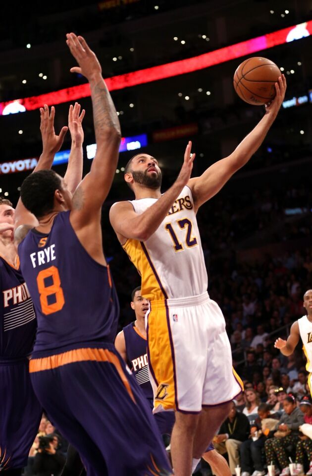 Lakers point guard Kendall Marshall, right, puts up a shot over Phoenix Suns forward Channing Frye during the first half of Sunday's game at Staples Center.