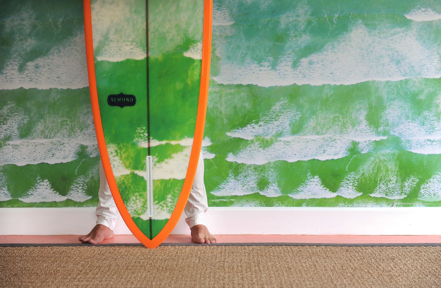 Malin stands behind a surfboard imprinted with his "Cape Town Waves" image.