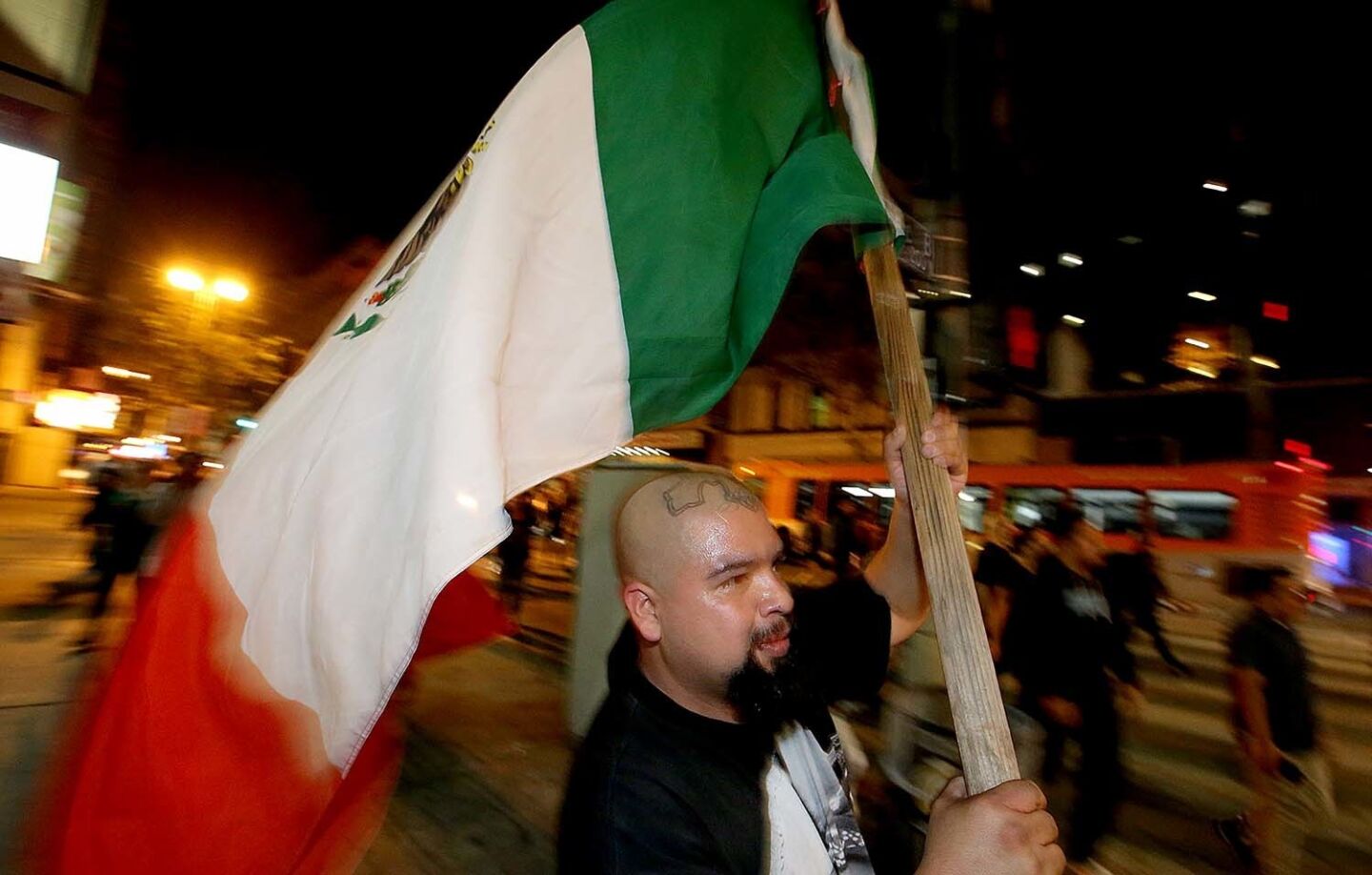 A anti-Trump demonstrator waves a large Mexican flag as protesters on the march snarl traffic in downtown Los Angeles.