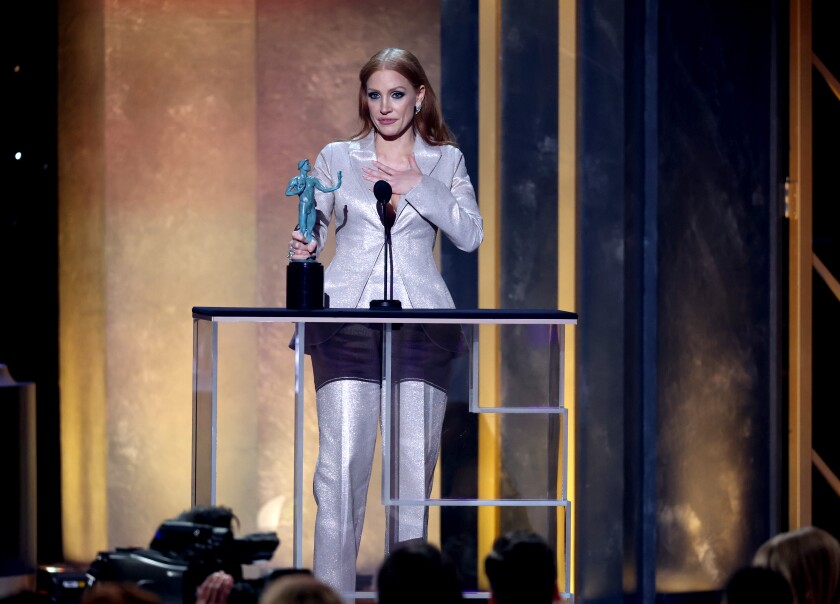 Jessica Chastain holds on hand to her chest, the other is on her SAG Award.