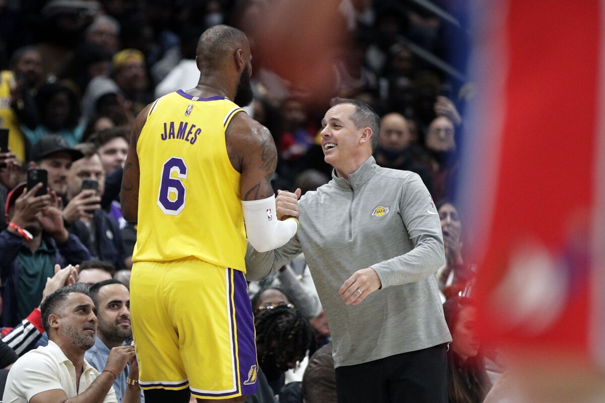 The Lakers' LeBron James is congratulated by coach Frank Vogel after moving into second place on the career scoring list.