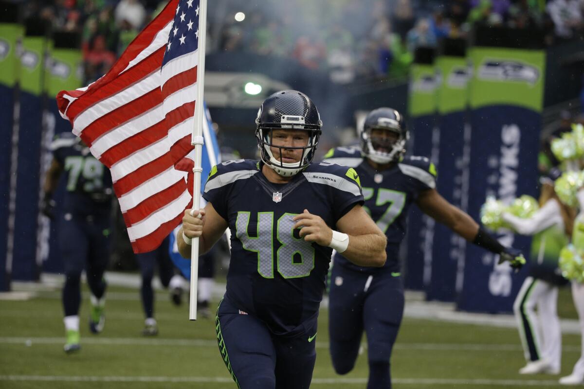 Seattle Seahawks long snapper and military veteran Nate Boyer runs out of the tunnel with a U.S. flag at the start of an exhibition game against the Denver Broncos on Aug. 14.