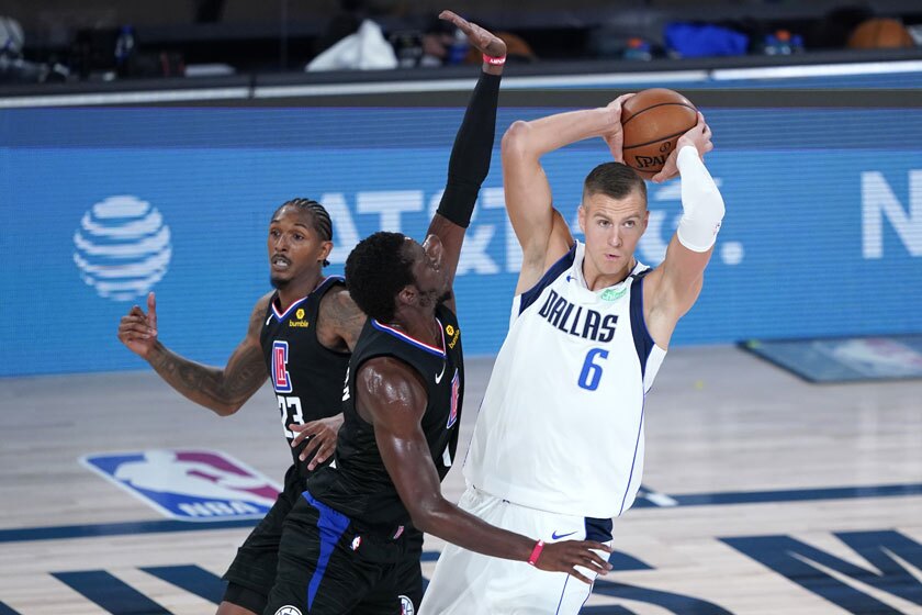 Dallas Mavericks center Kristaps Porzingis looks to pass over Clippers forward Reggie Jackson.