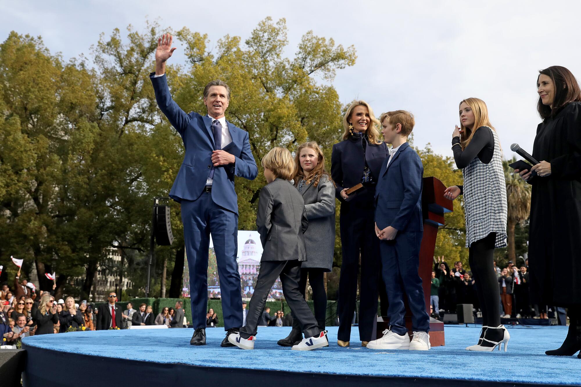 Gov. Gavin Newsom waves from stage with his family.