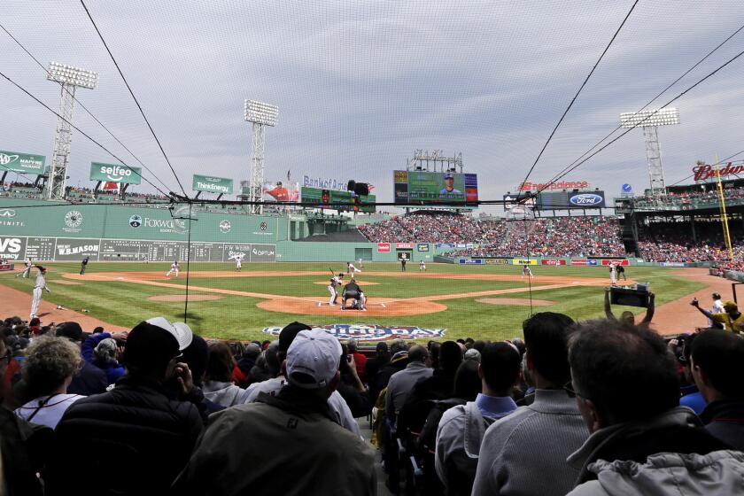 Fans watch behind protective netting installed at Fenway Park during the first inning of the Red Sox's home opener on April 11.