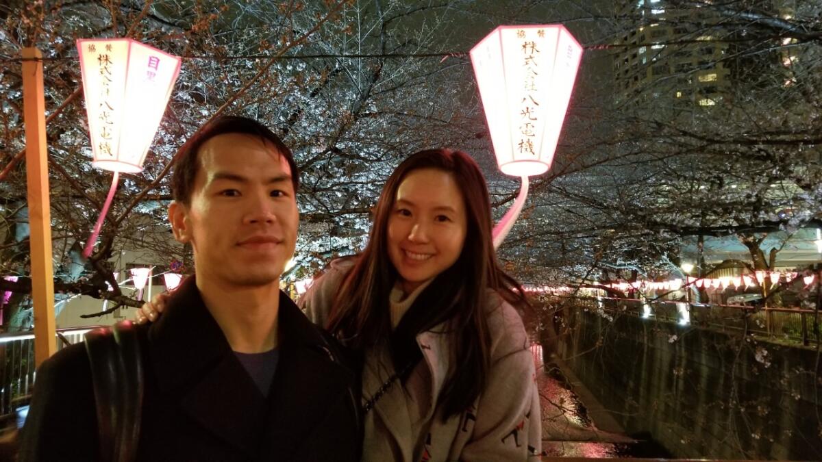 A couple pose for a photo under lighted paper lanterns