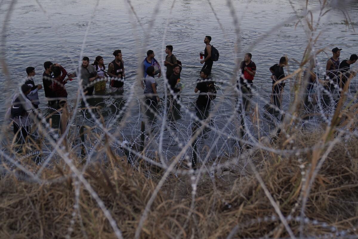 People stand in a river near concertina wire.