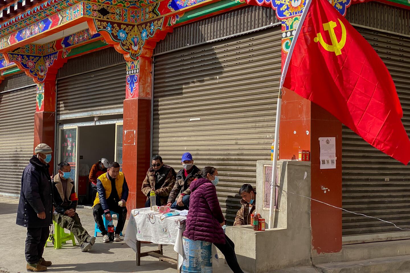 Virus prevention workers sit with a large Chinese Communist Party flag in Garze on Feb. 12, 2020.