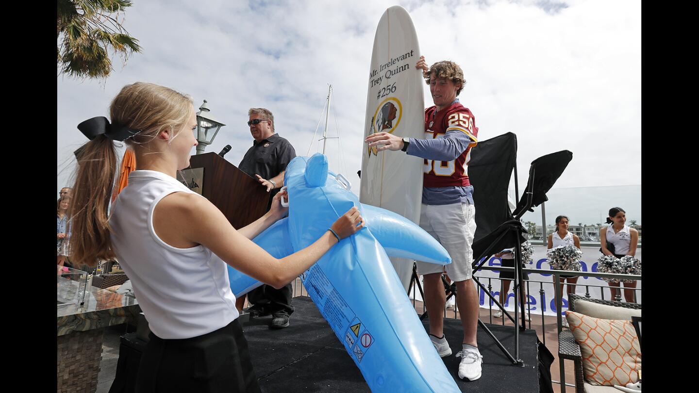 Mr. Irrelevant XLIII, Trey Quinn, right, accepts a surfboard and inflatable shark, gifted by Wayne Smith, top left, of Corona del Mar Properties during the "Welcome to Newport" festivities at the Balboa Bay Resort in Newport Beach on Saturday, June 16. Quinn, a rookie wide receiver, was selected 256th by the Washington Redskins.