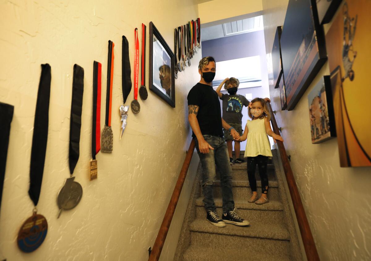 BMX star Simon Tabron stands in a stairwell of his Bonsall home with his 6-year-old twins, Scarlett and Dylan.