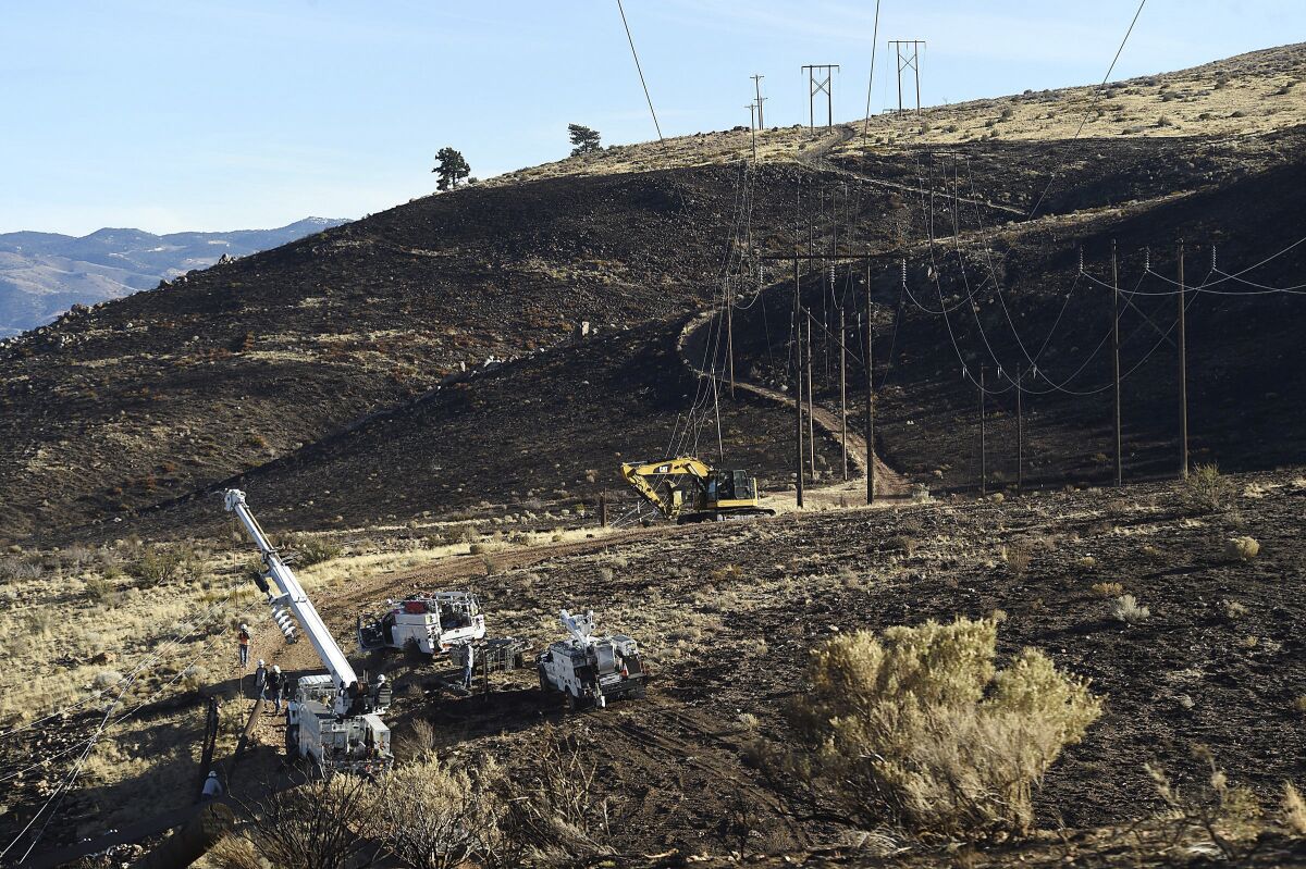 FILE - NV Energy repairs power lines are damaged in the area of origin of the Pinehaven Fire in Reno, Nev., on Nov. 19, 2020. Nevada's largest utility plans inspections of power lines this month in response to a request from plaintiffs in a lawsuit over a wildfire that damaged dozens of homes in Reno, a blaze that investigators blamed on arching power lines in gale force winds along the Sierra's eastern front in November 2020. (Jason Bean/The Reno Gazette-Journal via AP)